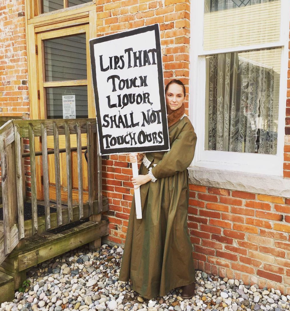 Hillary portraying Sarah Flowers, who died in 1892, at the Flat Rock Historical Society's annual Cemetery Walk. Holding a sign saying "lips that touch liquor shall not touch ours."